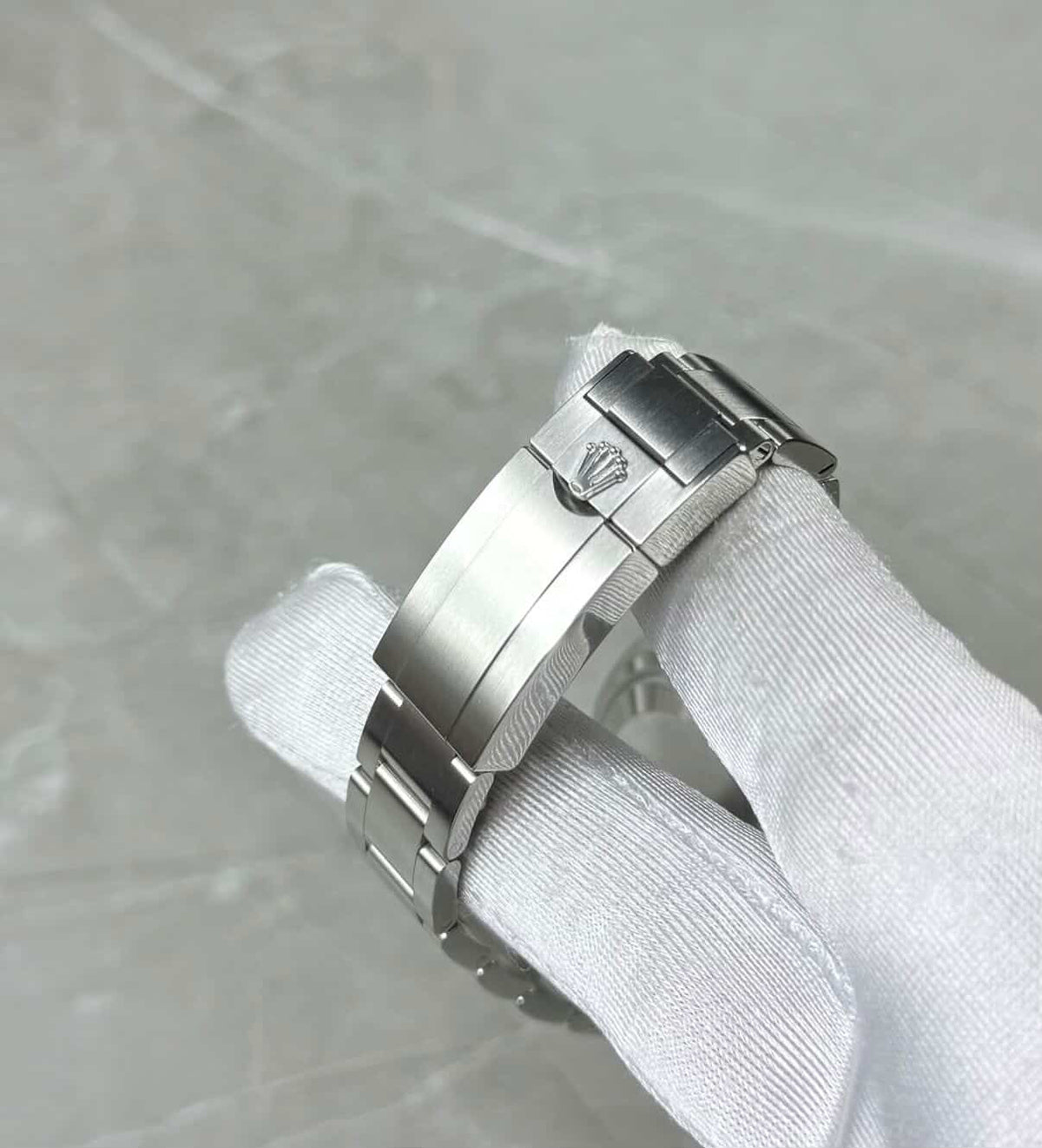 Rolex Explorer close-up of the crown-logo folding clasp in a white glove.
