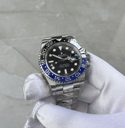 Rolex GMT-Master II Batman held face-on in a white glove showing black dial and blue-and-black bezel.