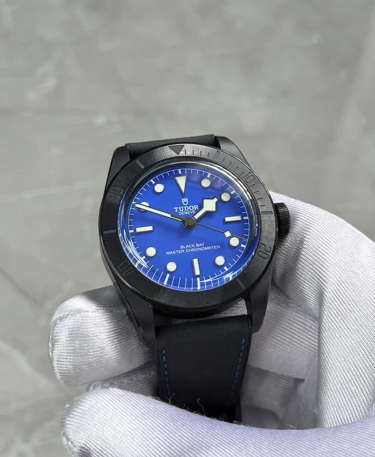 Tudor Black Bay Ceramic held in a white glove showing blue dial and dark case.