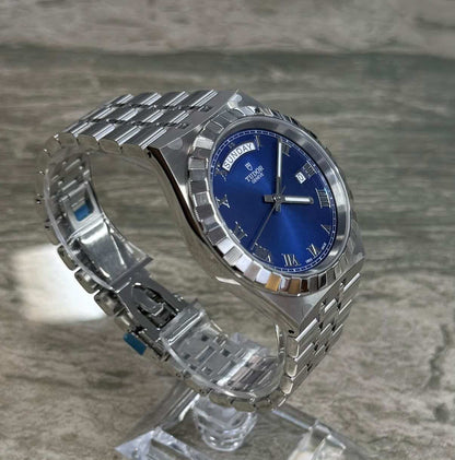 Tudor Royal Day Date opposite angled view on a clear stand showing blue dial, notched bezel and integrated bracelet.