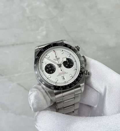 Tudor Black Bay Chronograph Panda held in a white glove showing white dial and two black subdials.