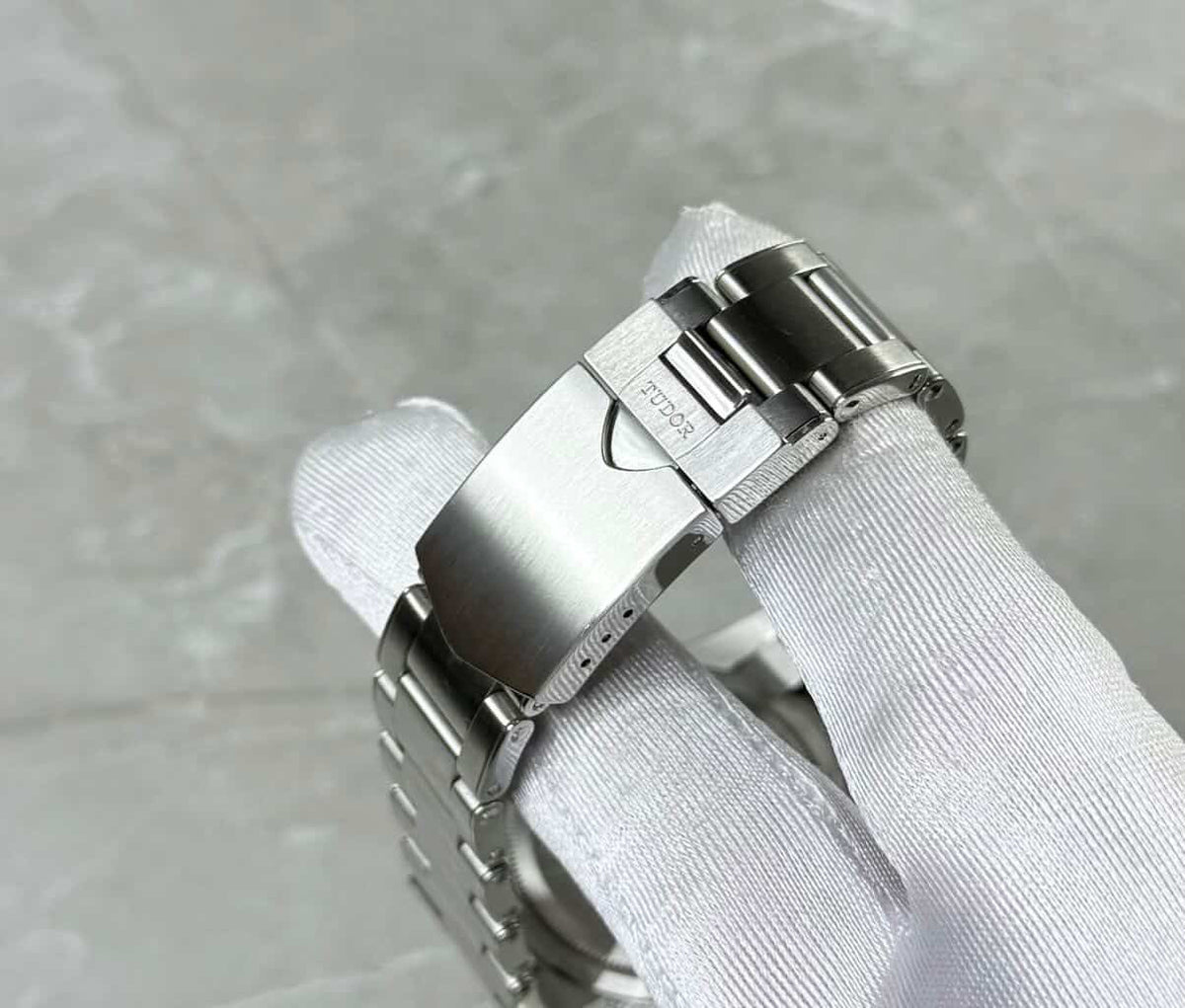 Tudor Black Bay Chronograph Panda close-up of the shield-logo folding clasp in a white glove.