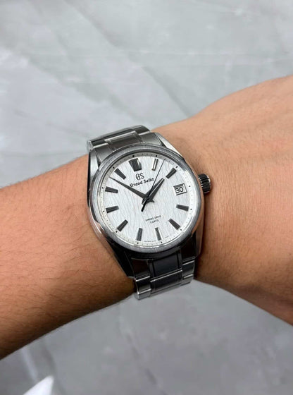 Grand Seiko White Birch on wrist with white dial and silver-tone bracelet.