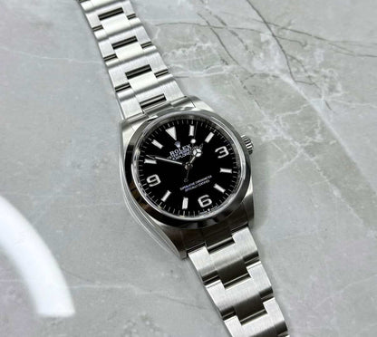 Rolex Explorer lying flat with black dial, large 3, 6 and 9 numerals and three-link bracelet.