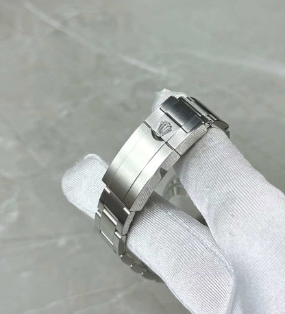 Rolex Explorer close-up of the crown-logo folding clasp in a white glove.