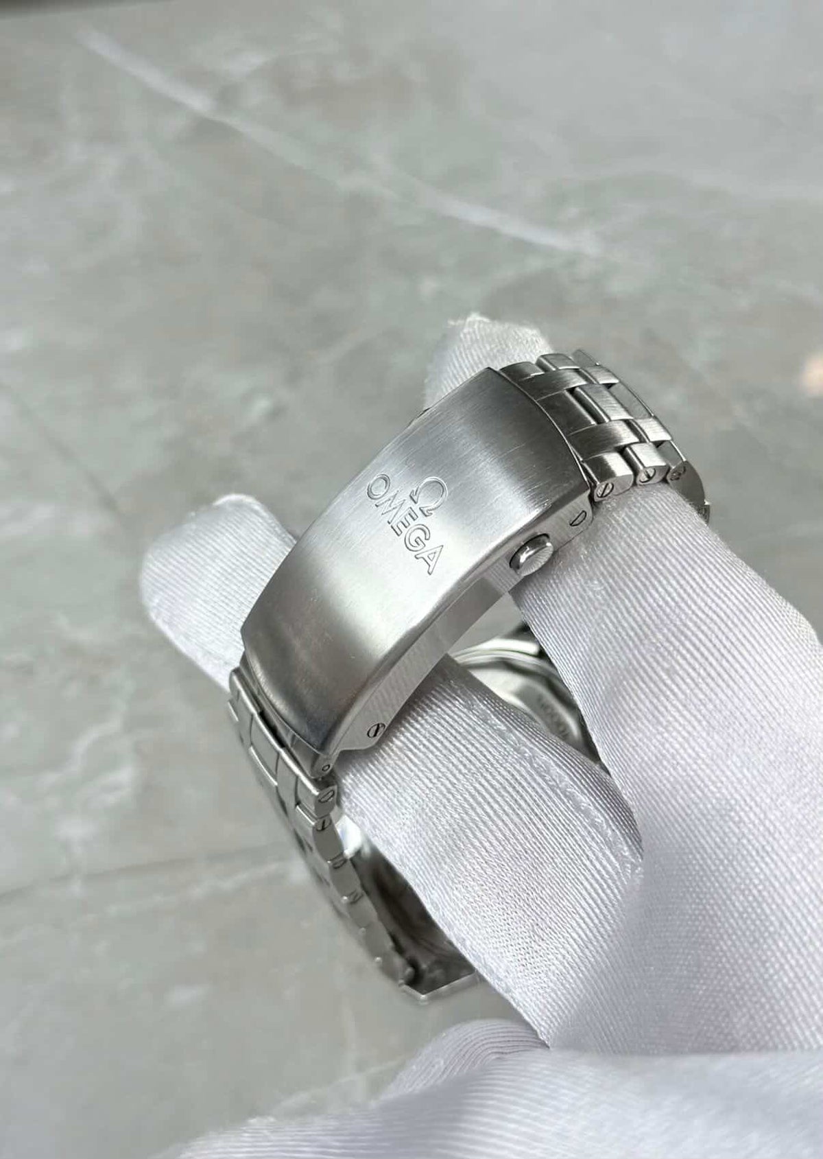 Omega Seamaster Diver 300M close-up of the branded folding clasp held in a white glove.