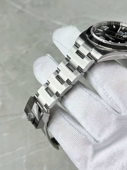 Rolex Explorer 40 Oyster bracelet across a white glove, with the case side and black dial partly visible.