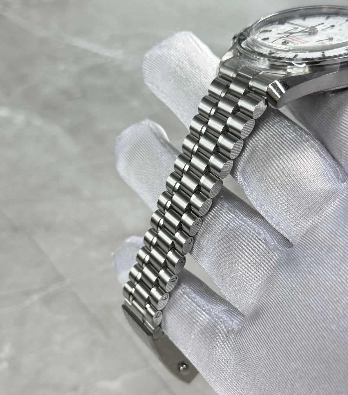 Omega Speedmaster bracelet close-up showing narrow links and case edge beneath the white dial.