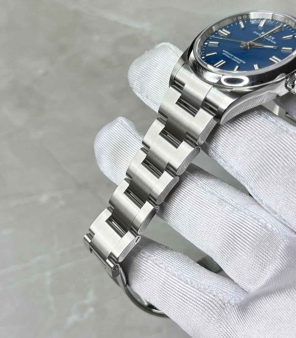 Rolex Oyster Perpetual 36 bracelet close-up showing broad centre links, crown and blue dial edge.