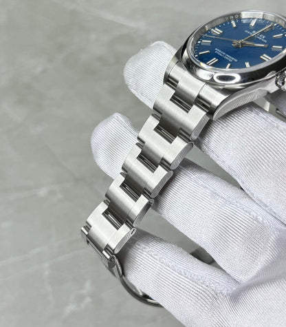 Rolex Oyster Perpetual 36 bracelet close-up showing broad centre links, crown and blue dial edge.