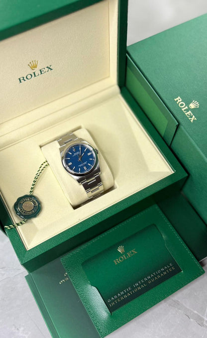 Rolex Oyster Perpetual 36 displayed in an open green box with cream interior, tag and green printed packaging.