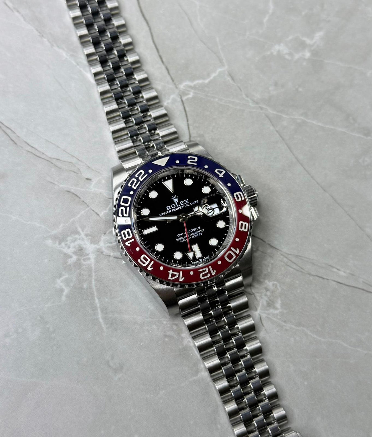 Rolex GMT-Master II Pepsi lying flat with black dial, red-and-blue bezel and five-link bracelet.