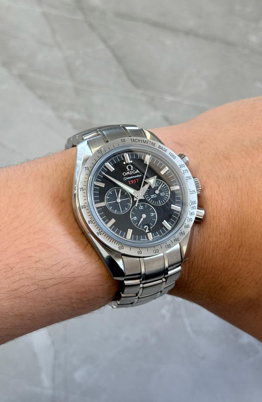 Omega Speedmaster Broad Arrow on wrist with black dial, silver-tone bezel and bracelet.