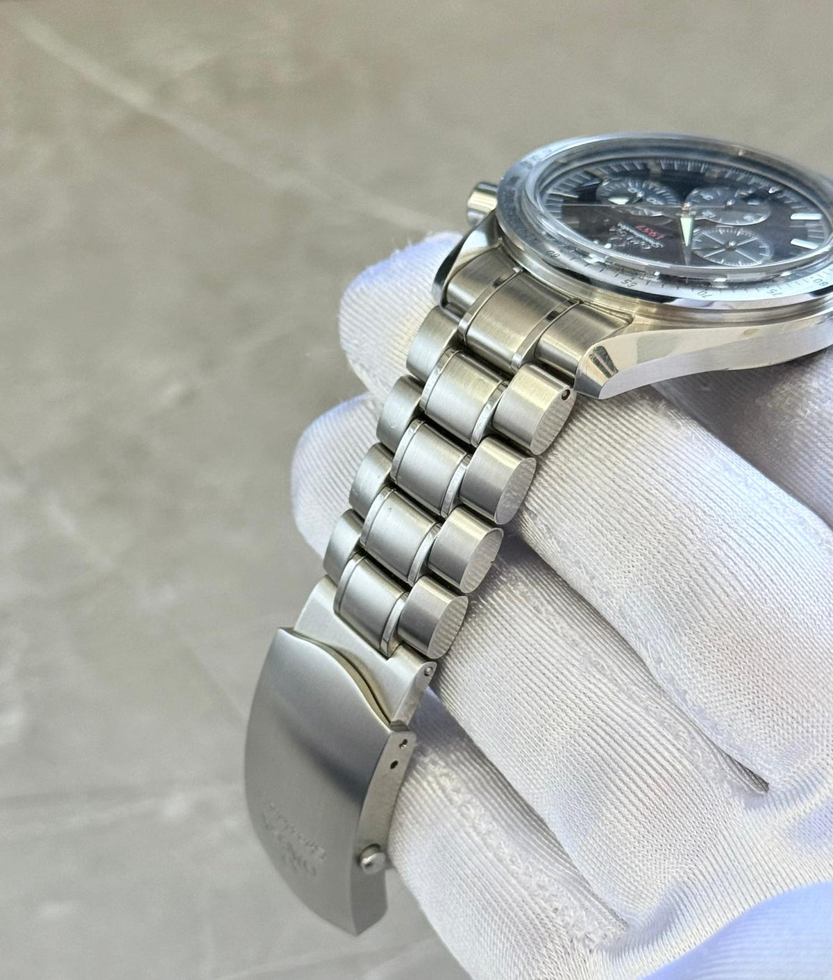 Omega Speedmaster Broad Arrow angled bracelet view showing rounded links and open folding clasp beneath the case.