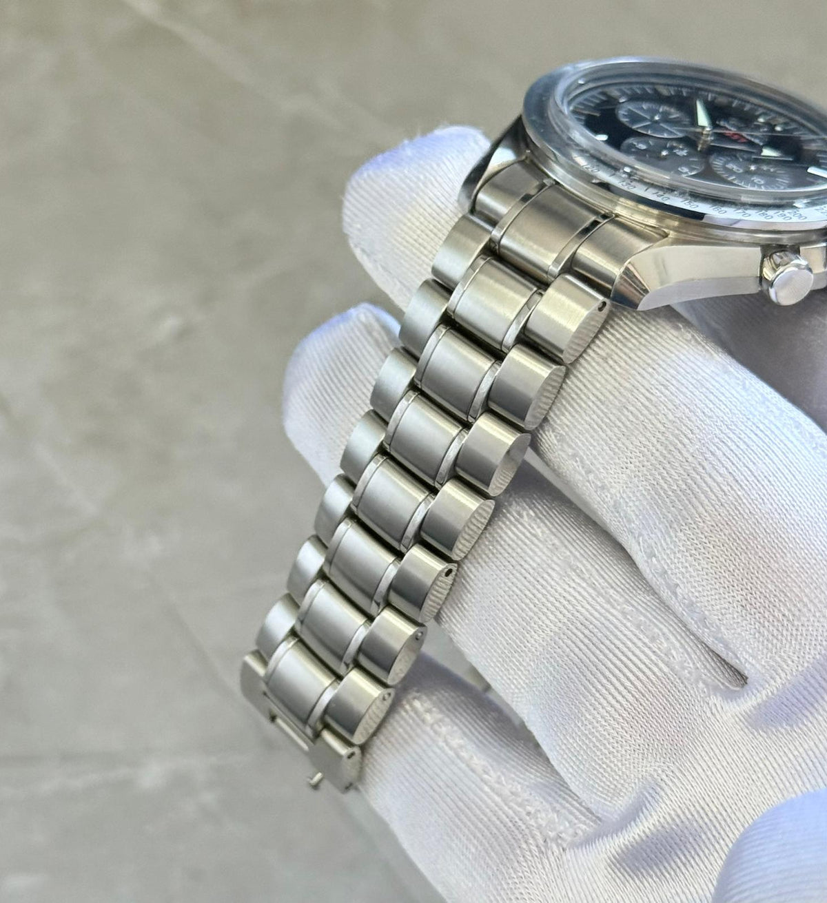 Omega Speedmaster Broad Arrow bracelet close-up showing rounded multi-part links and crown-side case edge.
