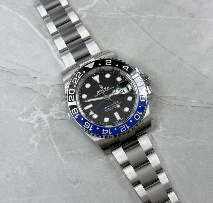 Rolex GMT-Master II Batman lying flat with black dial, blue-and-black bezel and three-link bracelet.