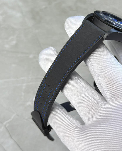 Tudor Black Bay Ceramic angled strap view in a white glove showing blue stitching and case edge.