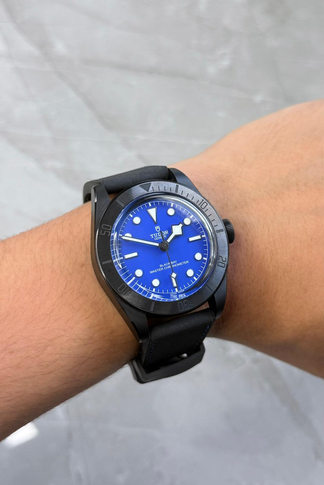 Tudor Black Bay Ceramic on wrist with blue dial and black strap.