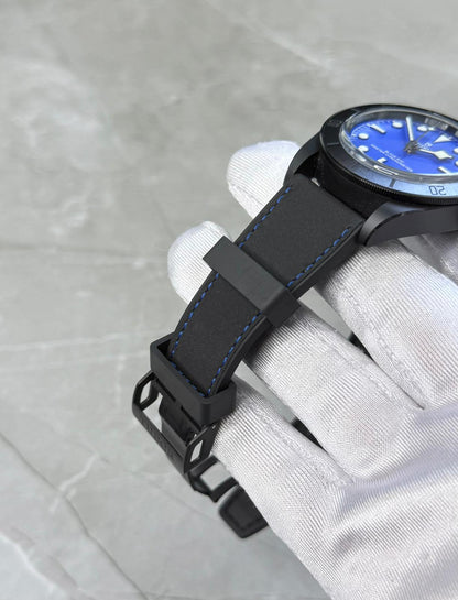 Tudor Black Bay Ceramic strap close-up showing blue stitching, keepers and dark buckle beneath the case.